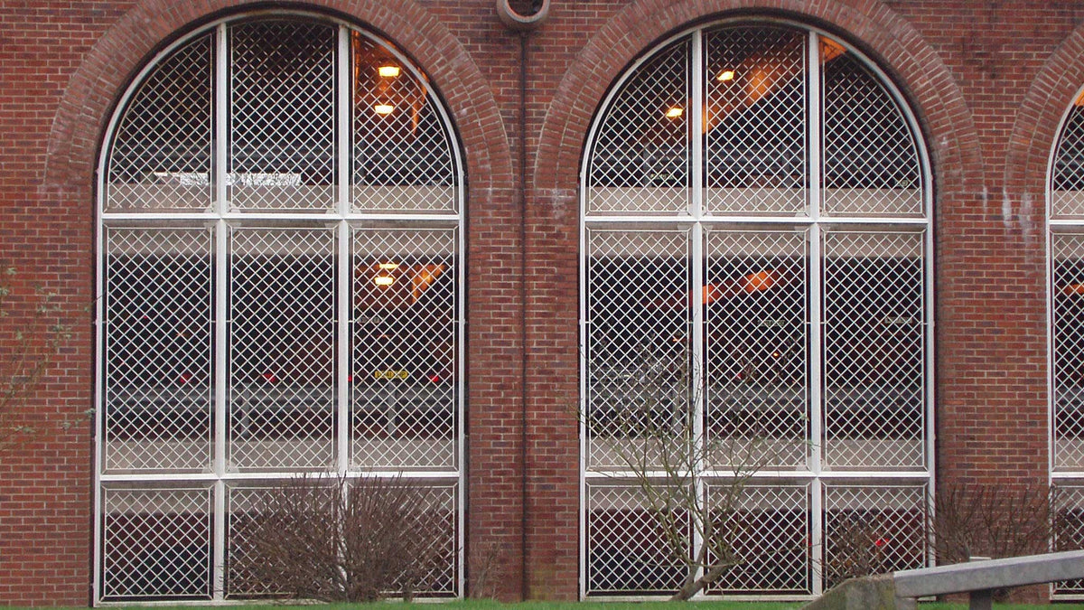 White diamond security grilles installed in arched brick building windows