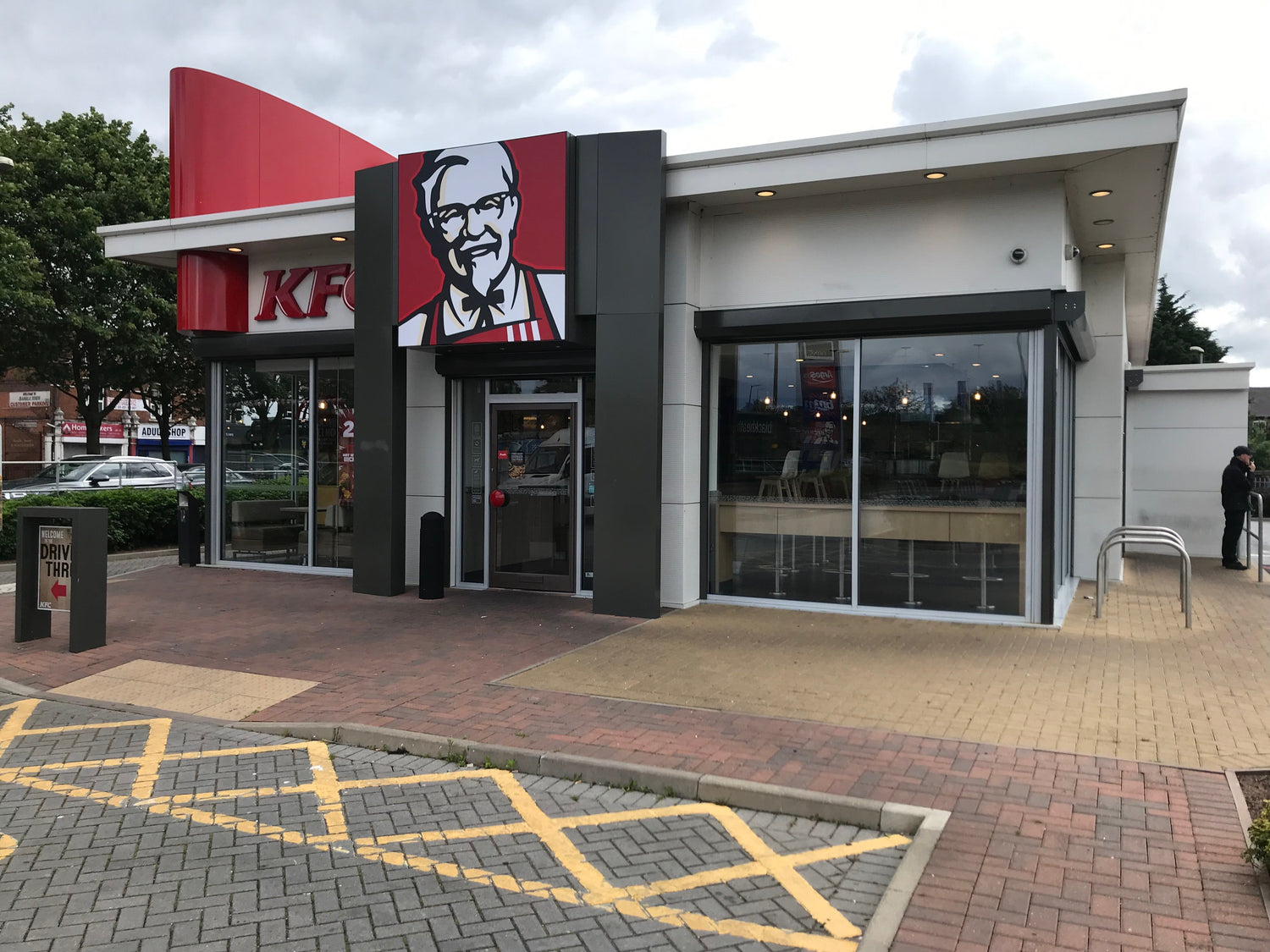 KFC restaurant exterior with glass doors, security shutters, and drive-thru signage