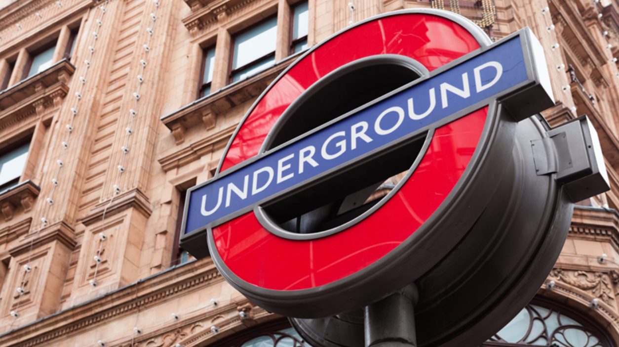 London Underground sign with red circle and blue bar, mounted on ornate building facade