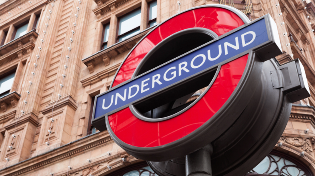 Close-up of the iconic red and blue London Underground roundel sign in front of a building.