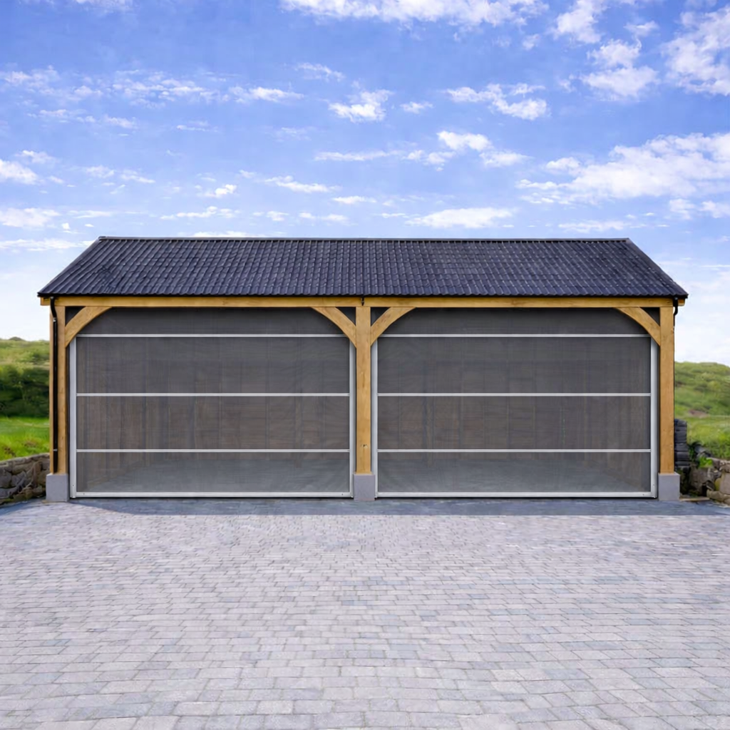 Wooden double garage with grey roller shutter doors and tiled roof under a blue sky.