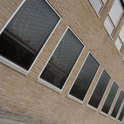 CrimeShield perforated window security mesh installed on a brick building facade