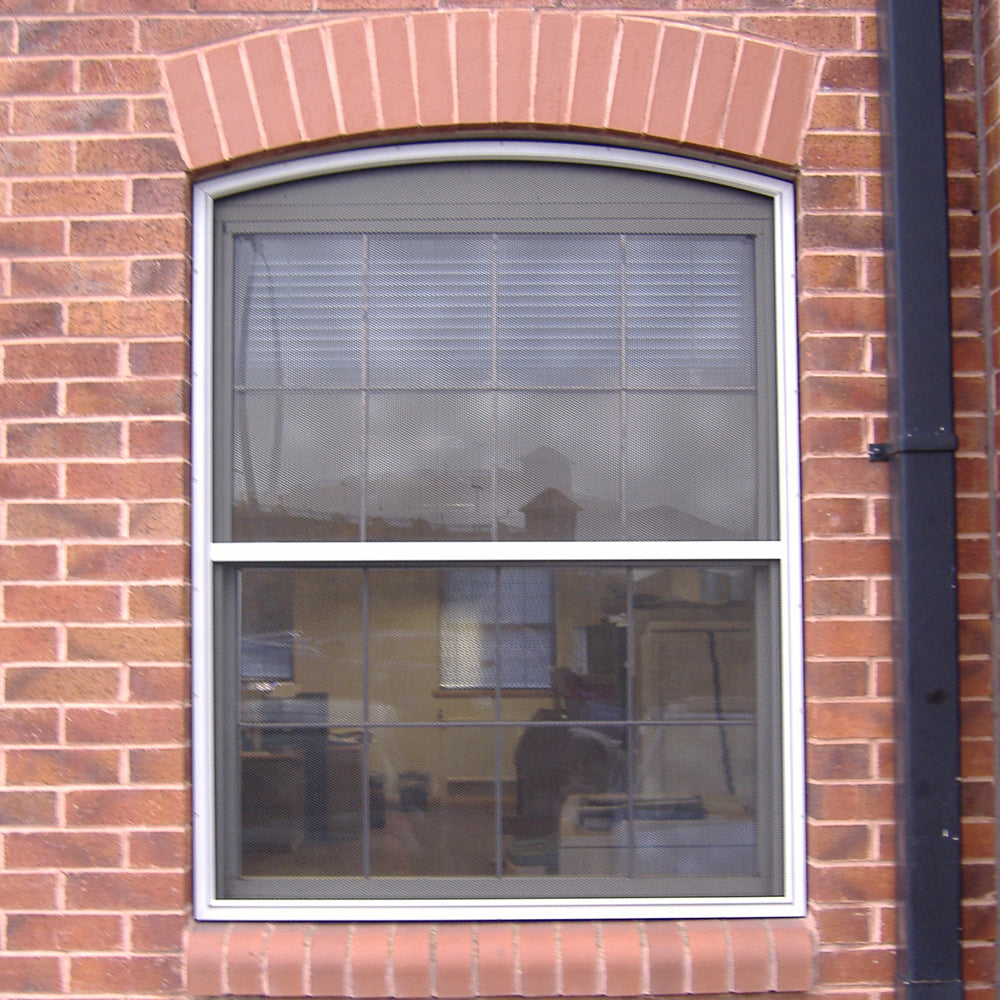 CrimeShield perforated window security mesh installed on a brick wall window