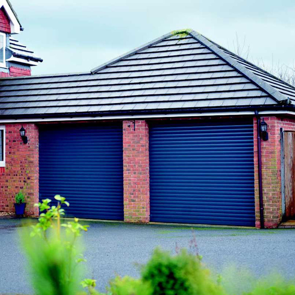 Blue roller shutter garage doors installed on a red brick building with a tiled roof.