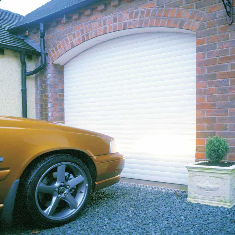 White automatic roller garage door installed in a red brick house exterior.