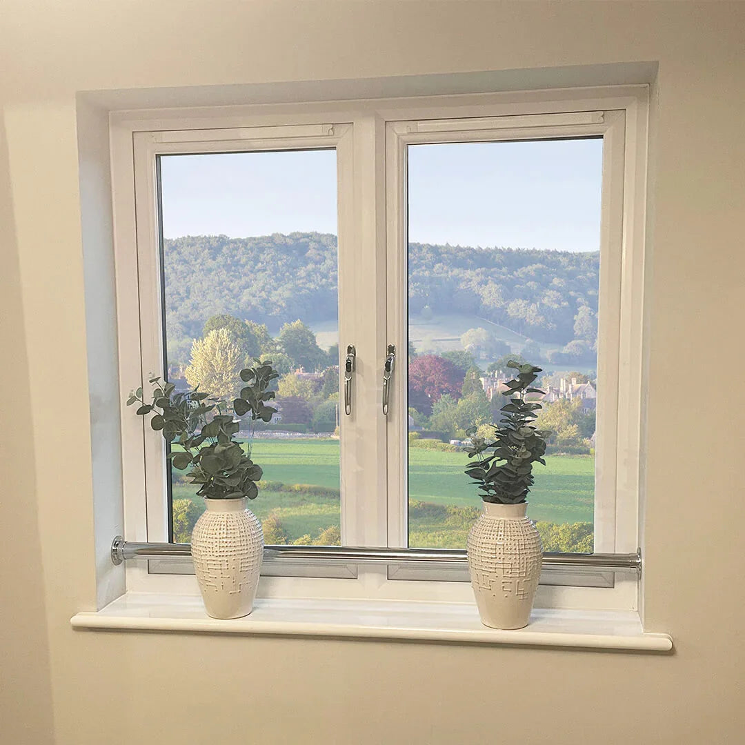 White double-glazed window with scenic countryside view, featuring security handles and decorative vases on sill